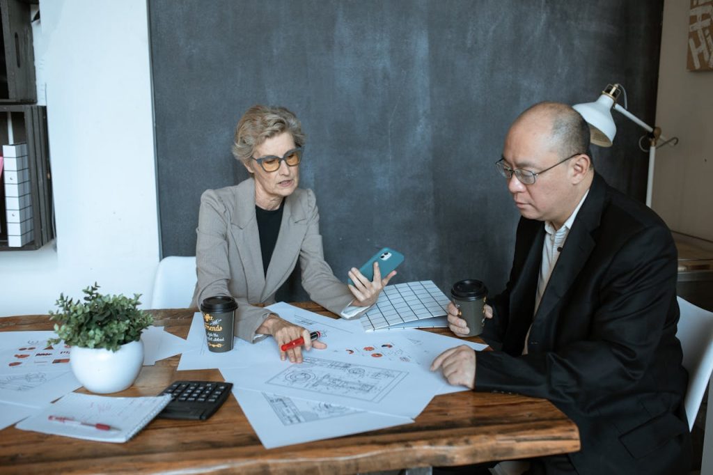 a-woman-and-a-man-working-together-in-an-office-5921552 Two business professionals discuss project designs at an office desk.