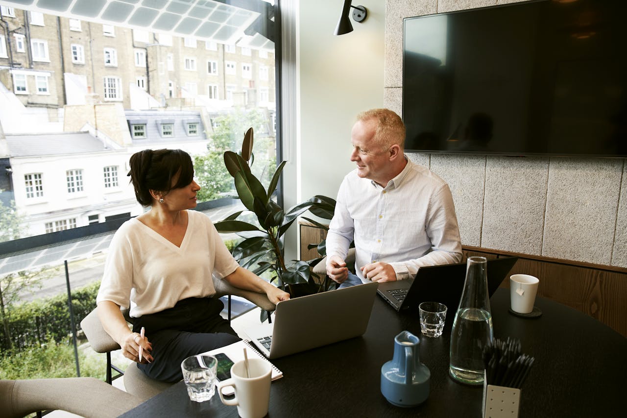 Mastering the First Impression: Your intriguing post title goes here Two business professionals engaging in a team meeting in a modern London office with a large window view.