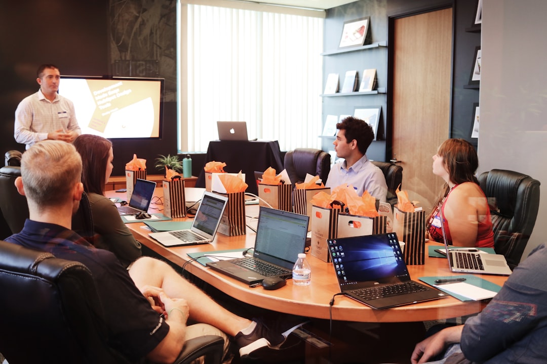 who-we-are man-standing-in-front-of-people-sitting-beside-table-with-laptop-computers-gmsnxqiljp4